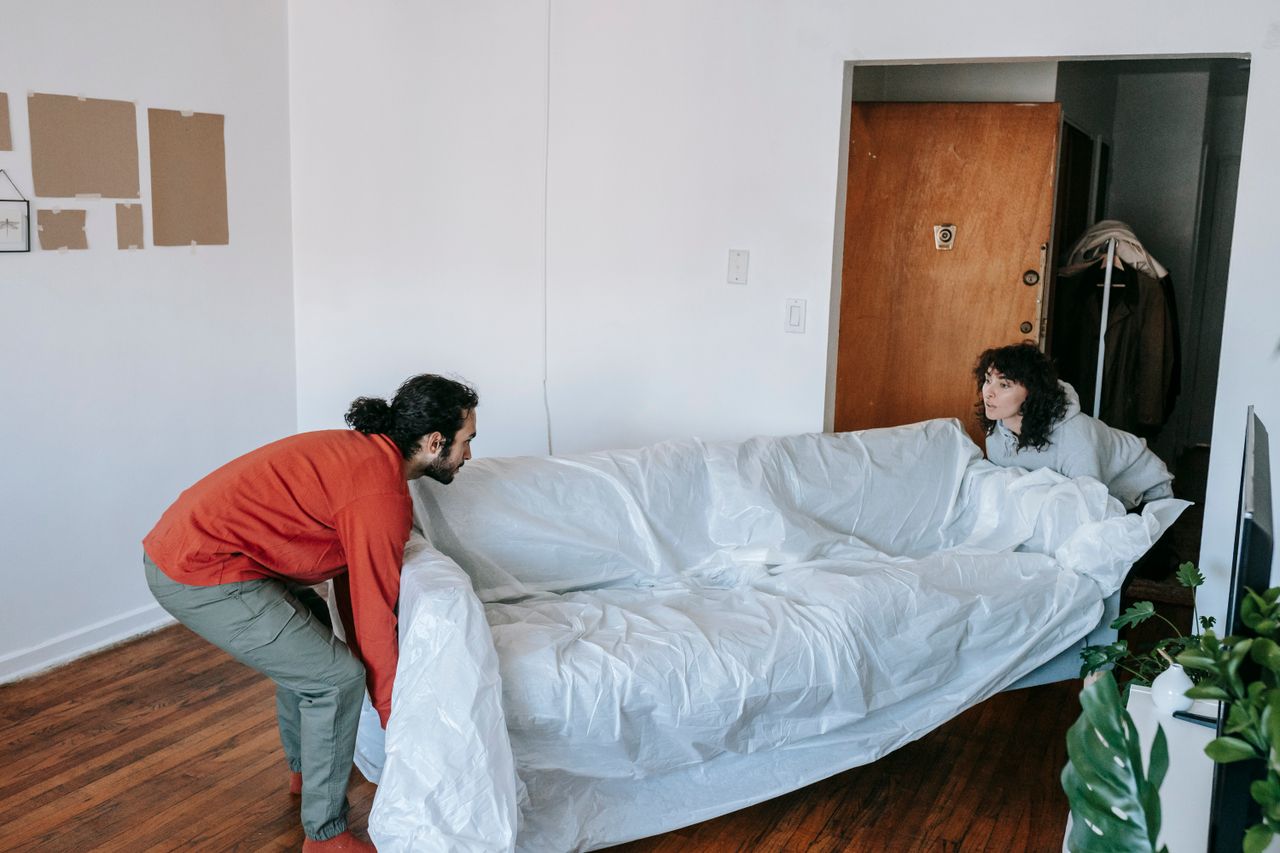 A couple working together to carry a couch while settling into a new apartment.